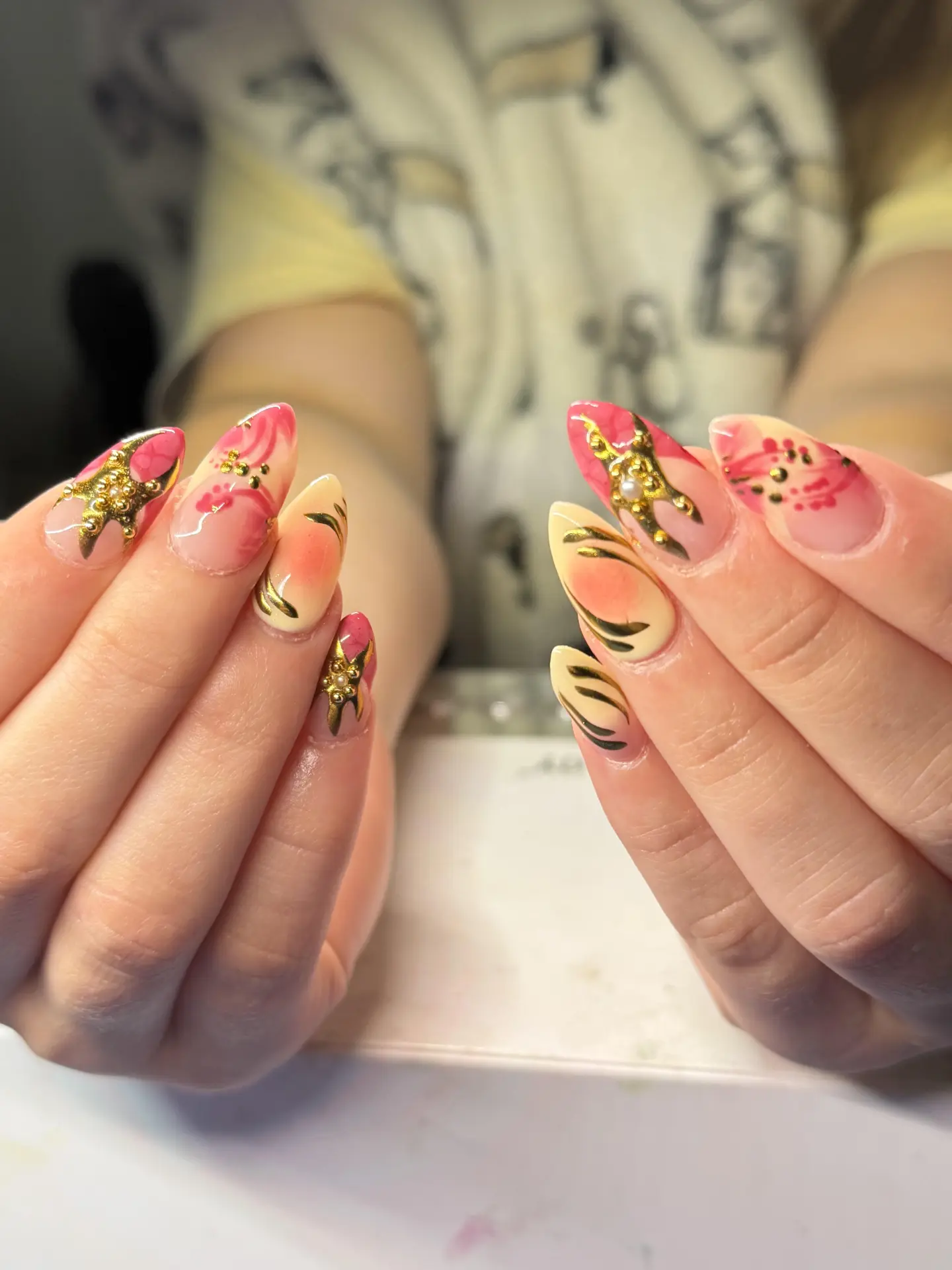 Blush and gold nail polish bottles on a marble tray with dried florals